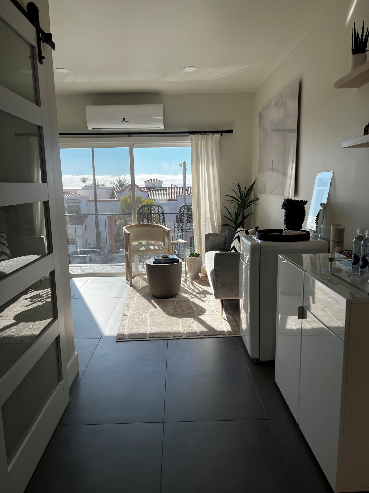 The waiting room at Skin Restore, San Clemente — natural light, ocean view and palms beyond the balcony
